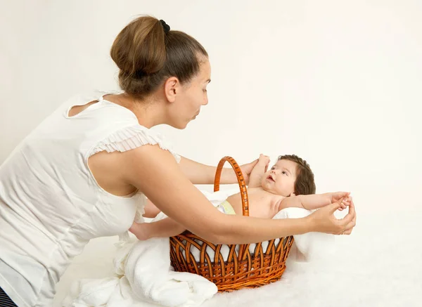 Mother talk with baby in basket on white towel, family concept, yellow toned — Stock Photo, Image