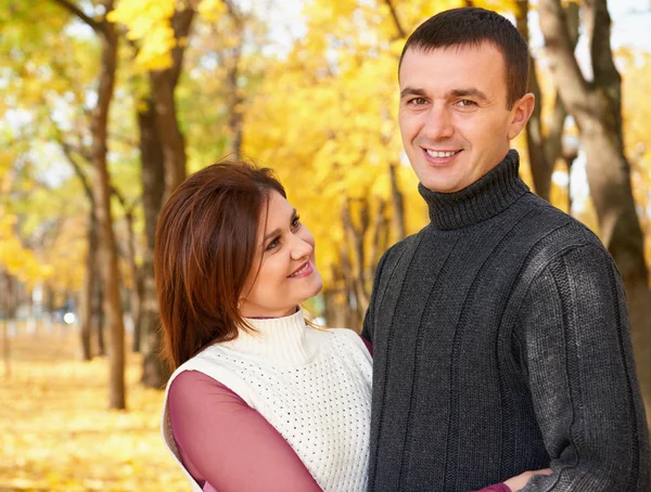 Glückliches erwachsenes Paar umarmt sich im herbstlichen Stadtpark, Bäume mit gelben Blättern, strahlende Sonne und glückliche Emotionen, Zärtlichkeit und Gefühle — Stockfoto