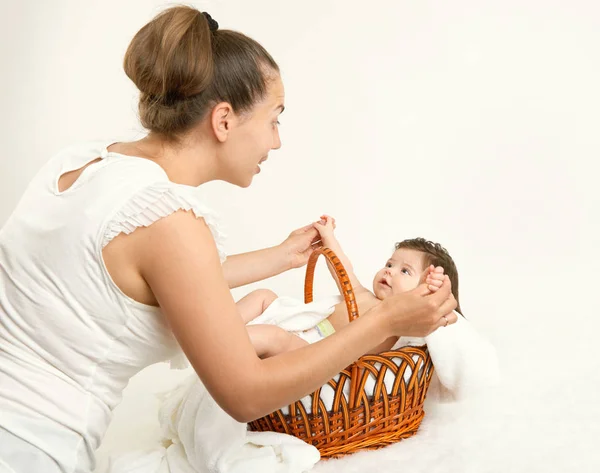 Mother talk with baby in basket on white towel, family concept, yellow toned — Stock Photo, Image