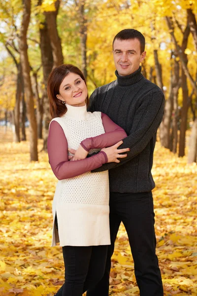 Romantic people, happy adult couple embrace in autumn city park, trees with yellow leaves, bright sun and happy emotions, tenderness and feelings — Stock Photo, Image