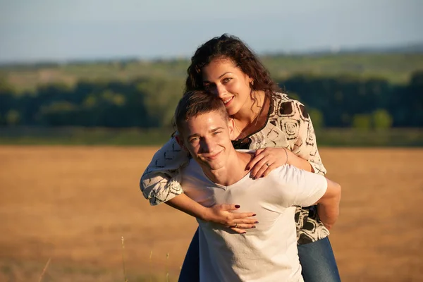 Vacaciones, senderismo, amor y concepto de amistad - pareja sonriente divirtiéndose sobre el fondo del cielo nocturno, temporada de verano, chica cabalgando sobre el hombre de vuelta — Foto de Stock