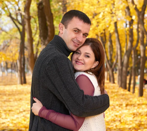 Romantische Menschen, glückliches erwachsenes Paar umarmt sich im herbstlichen Stadtpark, Bäume mit gelben Blättern, strahlende Sonne und glückliche Emotionen, Zärtlichkeit und Gefühle — Stockfoto