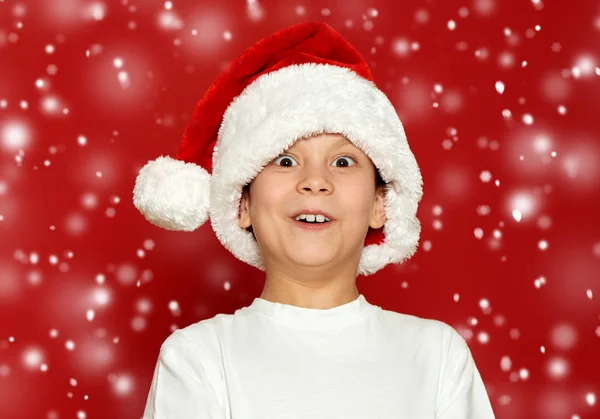 Здивований хлопчик дитячий портрет в капелюсі Санта на червоному, розважається і емоції, концепція зимового свята — стокове фото