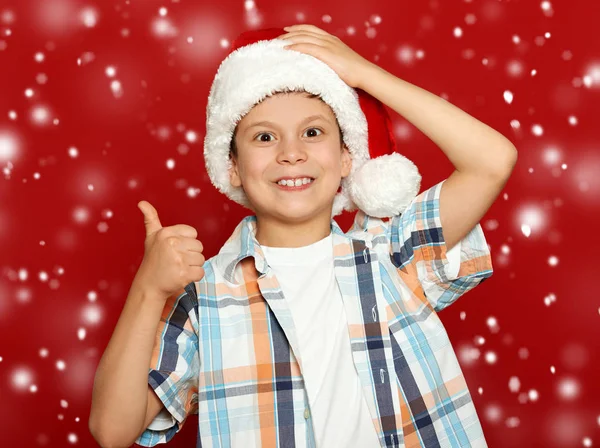 Портрет хлопчика в капелюсі Санта на червоному, розважається і емоції, концепція зимового свята — стокове фото