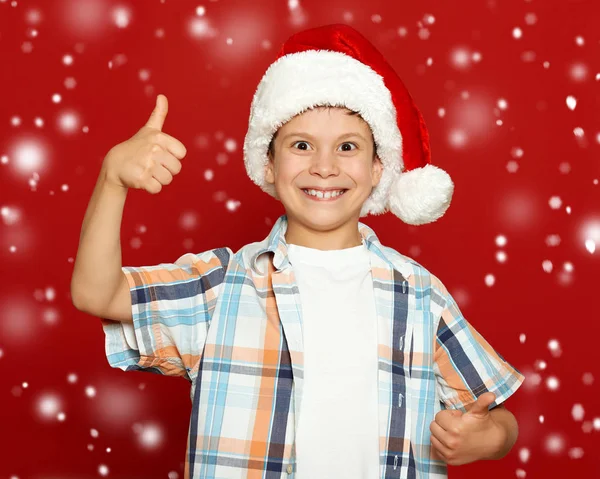 Портрет хлопчика в капелюсі Санта на червоному, розважається і емоції, концепція зимового свята — стокове фото