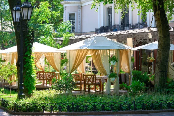 Street cafe interior in green city park, ornate with flowers, summer season, bright sunny day — Stock Photo, Image