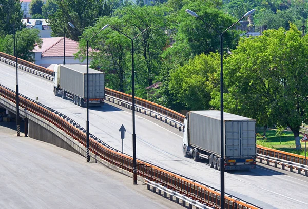 LKWs, die die Brücke hochfahren, Frachttransport, Liefer- und Versandkonzept, grüne Bäume im Hintergrund — Stockfoto