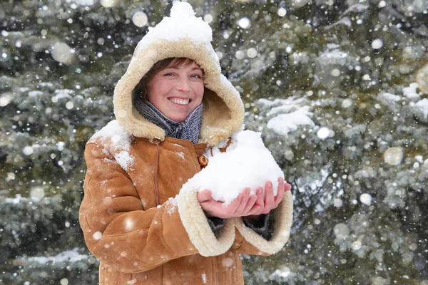 Hermosa mujer jugar con nieve en invierno al aire libre, abetos nevados en el bosque, con un abrigo de piel de oveja — Foto de Stock