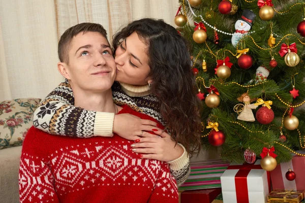 Ευτυχισμένο ζευγάρι με το δώρο Χριστουγέννων και Πρωτοχρονιάς στο σπίτι. Έλατο με διακόσμηση. Χειμερινές διακοπές έννοια. Χαμογελώντας οικογένεια μαζί. — Φωτογραφία Αρχείου