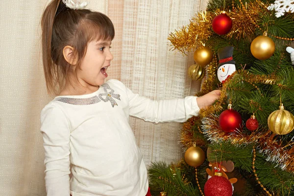 Retrato menina feliz na decoração de Natal, conceito de férias de inverno, árvore de abeto decorado e presentes — Fotografia de Stock