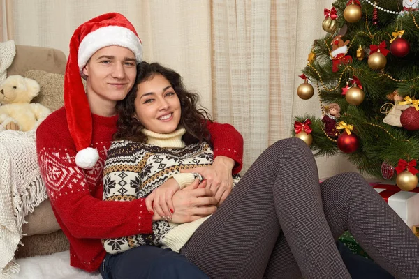 Coppia giovane nella decorazione natalizia. Interno casa con regali e abete. Concetto di vacanza di anno nuovo. Amore e tenerezza . — Foto Stock