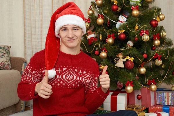 Young man in christmas decoration. Home interior with gifts and fir tree. New year holiday concept. — Stock Photo, Image