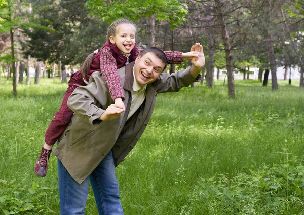 Apja játszó gyermek lány nyári park, a napfényt, a zöld fű és a fák — Stock Fotó