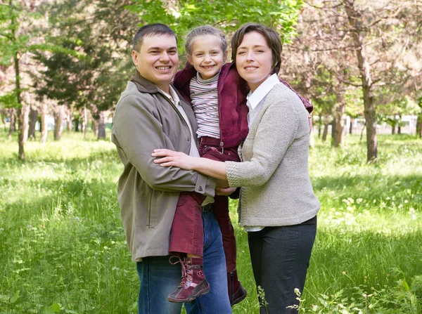 Família feliz e criança no parque de verão, bela paisagem com árvores e grama verde — Fotografia de Stock