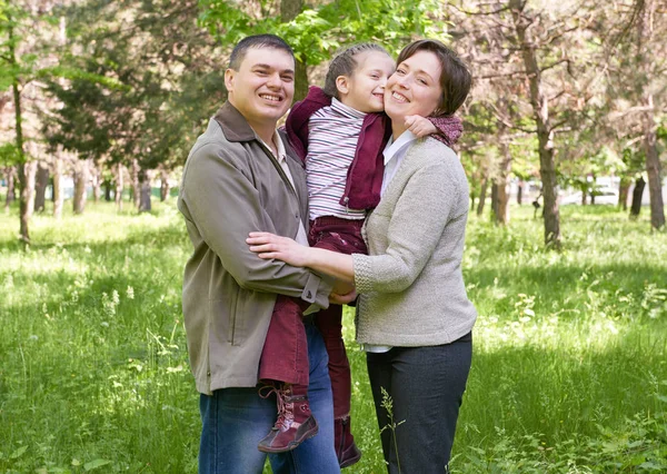 Šťastná rodina a dítě v létě park, krásná krajina se stromy a zelené trávy — Stock fotografie