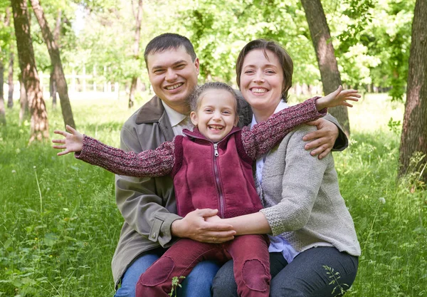 Šťastná rodina a dítě portrét. Městský park v letní sezóně. Krásná krajina se stromy a zelené trávy — Stock fotografie