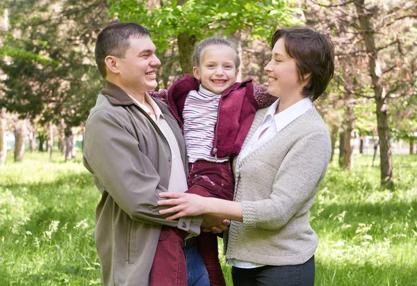 Šťastná rodina a dítě v létě park, krásná krajina se stromy a zelené trávy — Stock fotografie