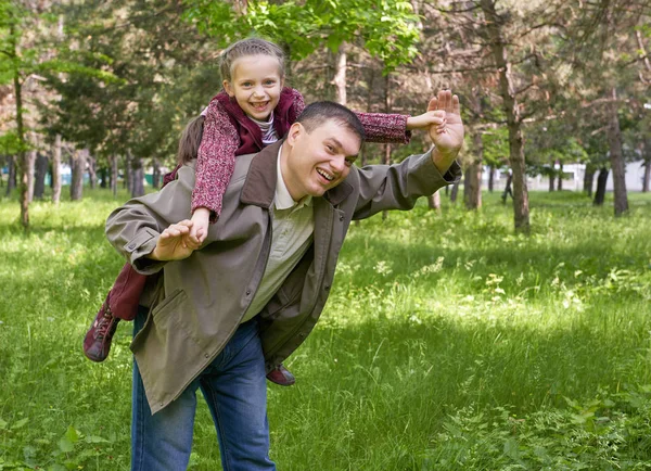 Far leker med barn flicka i sommaren park, solljus, grönt gräs och träd — Stockfoto