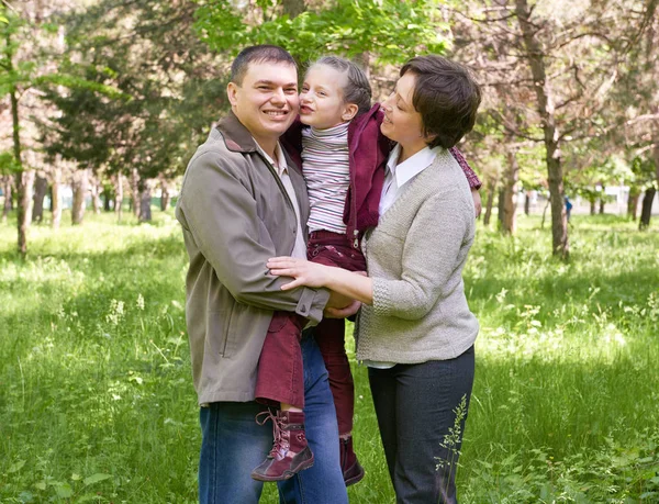 Família feliz e criança no parque de verão, bela paisagem com árvores e grama verde — Fotografia de Stock