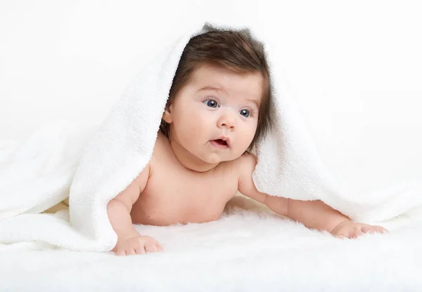 Baby liegt auf weißem Handtuch. Kind im Bett. der Kopf ist mit einer Decke bedeckt — Stockfoto