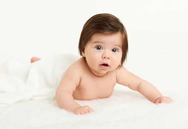 Adorably miminko leží na ručník v posteli, bílé pozadí. Šťastné dětství a zdravotnické koncepce. Žlutá, tónovaný — Stock fotografie