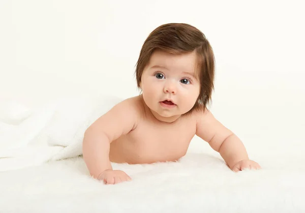 Adorably miminko leží na ručník v posteli, bílé pozadí. Šťastné dětství a zdravotnické koncepce. Žlutá, tónovaný — Stock fotografie