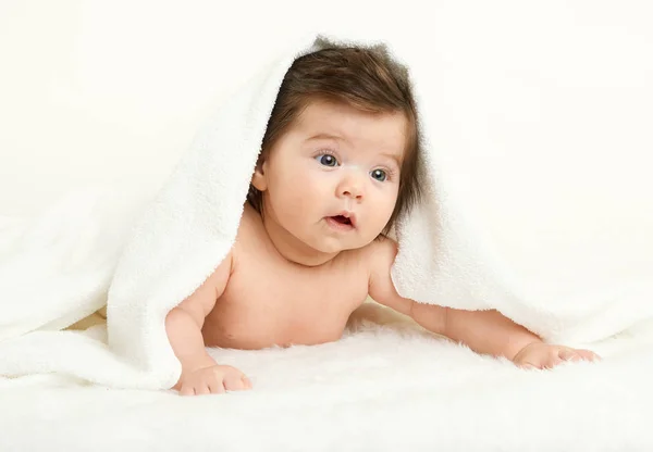 Baby lie on white towel. Child in bed. The head is covered with a blanket. Yellow toned. — Stock Photo, Image