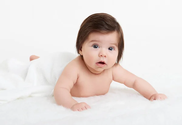 Adorably miminko leží na ručník v posteli, bílé pozadí. Šťastné dětství a zdravotnické koncepce — Stock fotografie