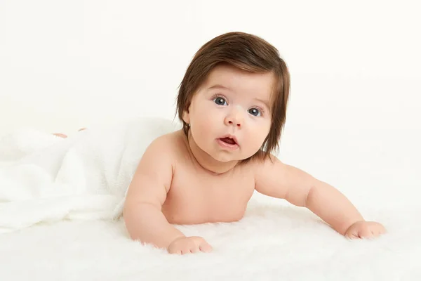 Adorably miminko leží na bílý ručník v posteli. Šťastné dětství a zdravotnické koncepce. Žlutá, tónovaný — Stock fotografie