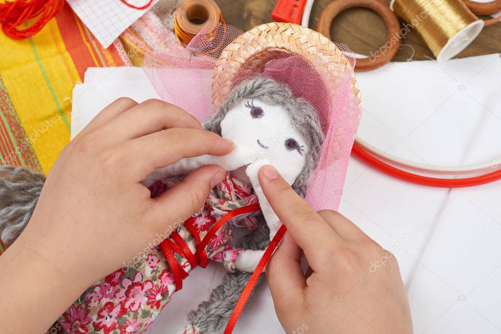 child hand making dress for handmade doll, learn to sewing
