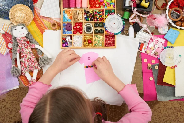 Chica cose ropa de muñeca, vista superior, accesorios de costura vista superior, costurera lugar de trabajo, muchos objetos para la costura, hecho a mano y artesanía — Foto de Stock