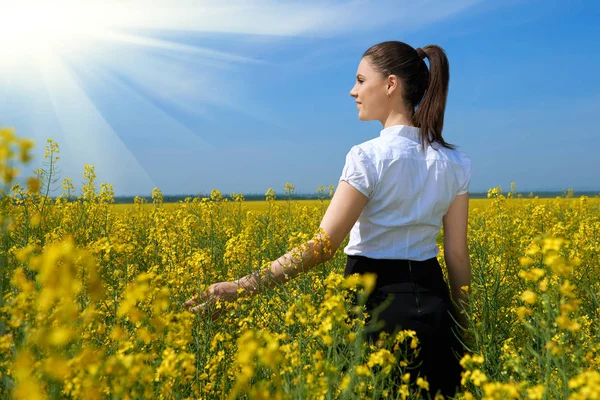 Mädchen im gelben Blumenfeld mit Sonne, schöne Frühlingslandschaft, strahlend sonniger Tag, Raps — Stockfoto