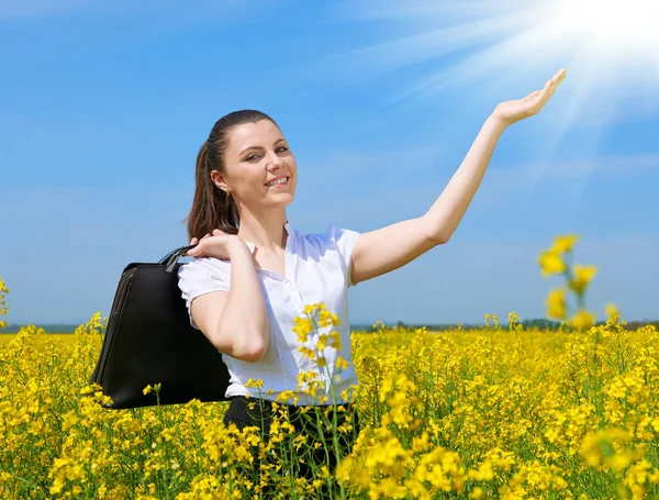 Geschäftsfrau mit Aktentasche entspannt sich im Blumenfeld unter der Sonne. junges Mädchen im gelben Rapsfeld. schöne Frühlingslandschaft, strahlend sonniger Tag — Stockfoto