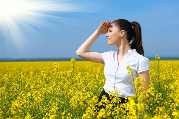 Geschäftsfrau blickt in die Ferne. junges Mädchen im gelben Blumenfeld. schöne Frühlingslandschaft, strahlend sonniger Tag, Raps — Stockfoto