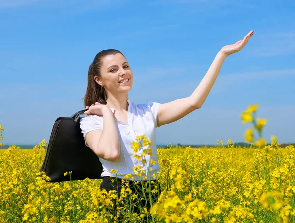 Geschäftsfrau mit Aktentasche entspannt sich im Blumenfeld unter der Sonne. junges Mädchen im gelben Rapsfeld. schöne Frühlingslandschaft, strahlend sonniger Tag — Stockfoto