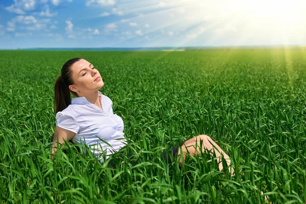 Mulher de negócios relaxando no campo de grama verde ao ar livre sob o sol. Menina bonita vestida de terno descansando, paisagem de primavera, dia ensolarado brilhante — Fotografia de Stock