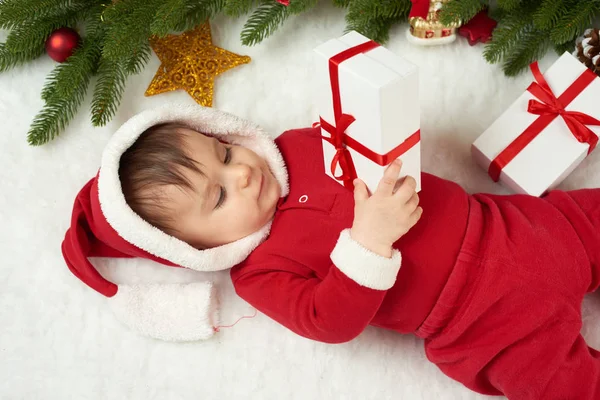 宝贝肖像的圣诞装饰，打扮成圣诞老人，躺在毛皮附近枞树和玩礼物，冬天假日概念 — 图库照片