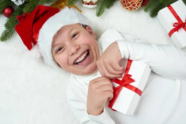 Menino criança se divertindo com decoração de Natal, expressão facial e emoções felizes, vestida com chapéu de Papai Noel, mentira no fundo de pele branca, conceito de férias de inverno — Fotografia de Stock