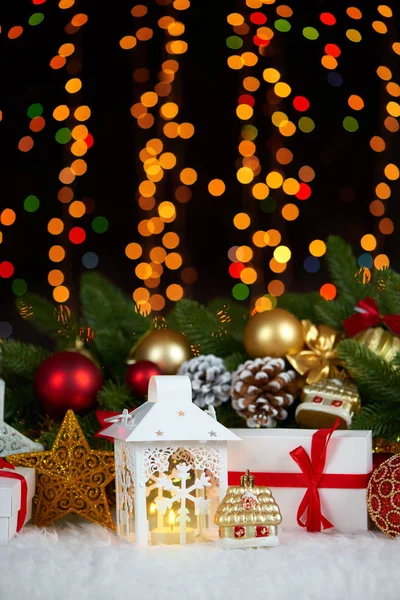 Decorazione natalizia su pelliccia bianca con primo piano ramo di abete, regali, palla di Natale, cono e altro oggetto su sfondo scuro con luci, concetto di vacanza invernale — Foto Stock