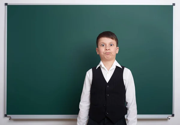 Elementary school boy near blank chalkboard background, dressed in classic black suit, one pupil, education concept — Stock Photo, Image
