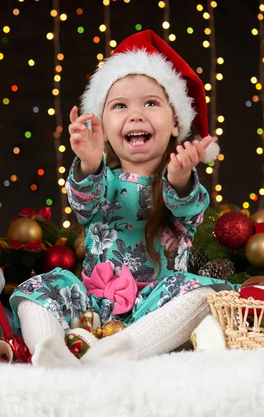 Bambino ragazza ritratto in decorazione di Natale, emozioni felici, concetto di vacanza invernale, sfondo scuro con illuminazione e luci boke — Foto Stock