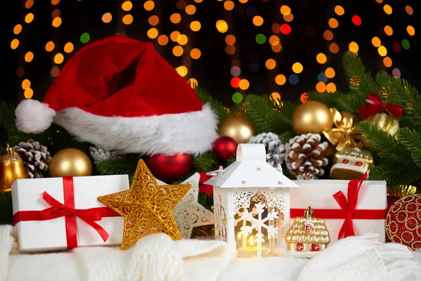 Рождественское украшение на белом мехе с веткой ели крупным планом, подарки, шар Xmas, конус и другие объекты на темном фоне с огнями, концепция зимнего отдыха — стоковое фото
