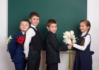 Kız çiçek, İlköğretim Okulu çocuğun yanında boş kara tahta arka plan, veren çocuklar giyinmiş klasik siyah takım elbise, grup öğrenci, eğitim kavramı