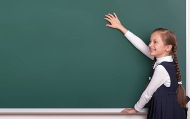 İlköğretim Okulu Kız kara tahta arka plan üzerinde el koymak ve boşluk giyinmiş klasik siyah takım elbise, grup öğrenci, eğitim kavramı göstermek