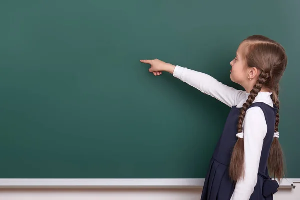 Scuola ragazza punta il dito vicino sfondo lavagna vuota, vestito in abito nero classico, allievo di gruppo, concetto di istruzione — Foto Stock