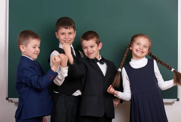Grupo aluno como uma gangue, posando perto de fundo quadro branco, sorridente e emoções, vestida com terno preto clássico — Fotografia de Stock
