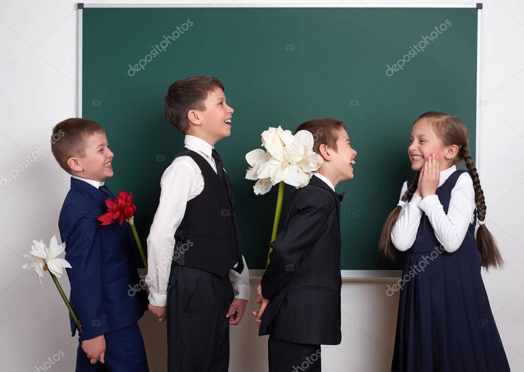 boys giving girl flowers, elementary school child near blank chalkboard background, dressed in classic black suit, group pupil, education concept