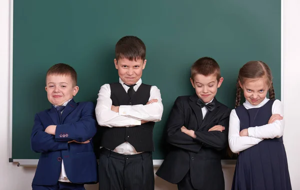 Gruppenschüler als Bande, posierend in der Nähe von leerem Kreidetafelhintergrund, Grimassen und Emotionen, gekleidet in einen klassischen schwarzen Anzug — Stockfoto