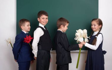 Kız çiçek, İlköğretim Okulu çocuğun yanında boş kara tahta arka plan, veren çocuklar giyinmiş klasik siyah takım elbise, grup öğrenci, eğitim kavramı