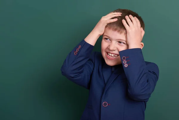 Very emotional school boy portrait near green blank chalkboard background, dressed in classic black suit, one pupil, education concept — Stock Photo, Image